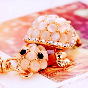 Macro detail of golden turtle keychain featuring translucent beads and crystal accents