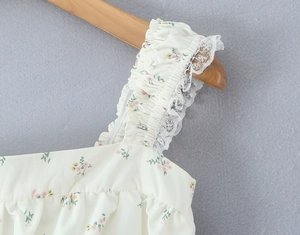Detail van bloemen top met kantafwerking en gerimpelde schouderbandjes in crème