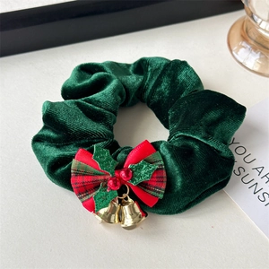 Close-up of velvet Christmas hair scrunchie with red plaid bow and golden bells