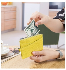 Detailed view of yellow lychee grain leather wallet held by hand with metal ring clip