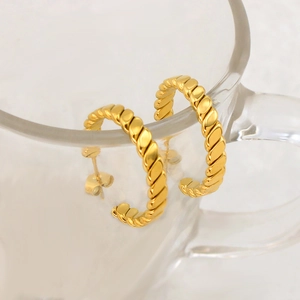 Elegant twisted gold C-shape hoop earrings in minimalist style on glass stand