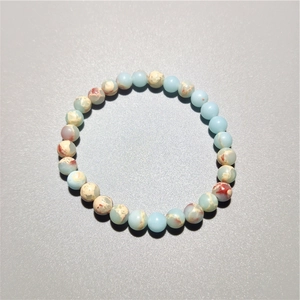 Close-up of polished natural stone beads bracelet with light blue and beige marble texture