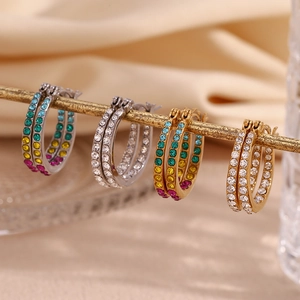 Detail view of gold and silver hoop earrings with rainbow and white crystals on silk
