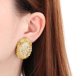 Detailed close-up of a vintage golden textured oval earring with micro-pave crystals on ear