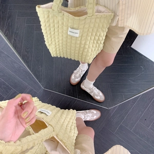 Mirror selfie showing the pale yellow green bubble texture tote bag on a dark floor
