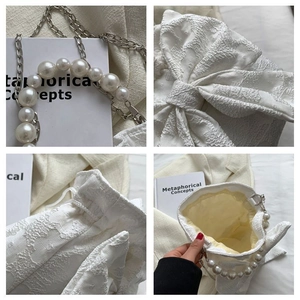 Detail of white jacquard handbag featuring pearl handle bow accent and chain strap