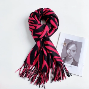 Detailed flat lay of zebra-striped cashmere scarf in magenta and black with soft fringe
