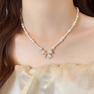 Close-up of sparkling zircon bow pendant on elegant pearl necklace worn by a model