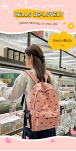 Sac à dos rose en velours côtelé avec motifs nœuds et ruban noir porté au dos
