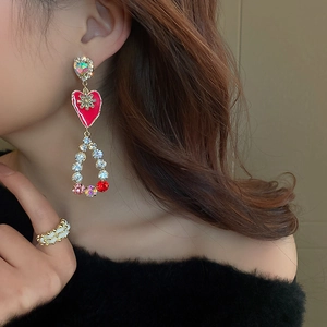 Detailed view of vintage long earrings with red enamel hearts and colorful rhinestones