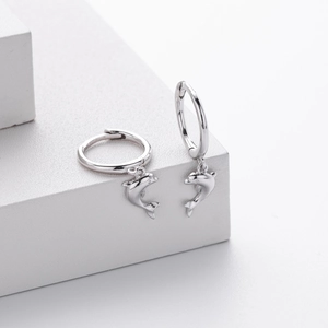 Detailed view of S925 sterling silver dolphin earrings on minimalist white display