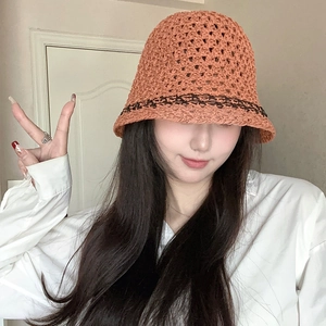 Detail of handwoven caramel straw bucket hat with dark stripes and hollow lace edge