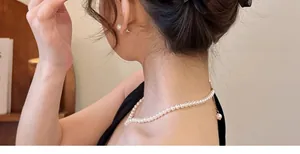 Elegante einlagige weiße Perlenkette und passende Ohrstecker an einem Modell