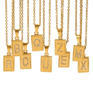 Detailed macro view of 18k gold plated square letter pendants with zircon inlay on fine chains