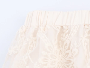 Detailed macro of elastic waistband and floral lace embroidery on a bohemian tiered skirt