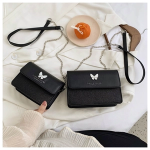 Detail of black crossbody bag featuring silver butterfly clasp and glitter finish
