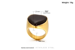 Macro view of wide gold stainless steel ring with an inlaid black heart natural stone