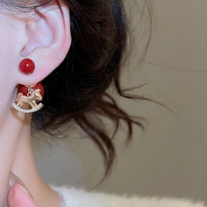 Close-up of 18K gold plated rocking horse earrings with red beads on a female model