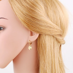 Detail view of a gold-plated earring with a zircon-encrusted sun cross on a female model