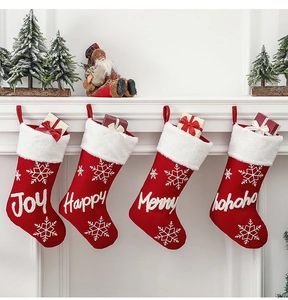 Detail of red knitted Christmas stockings with white faux fur cuffs and snowflake embroidery