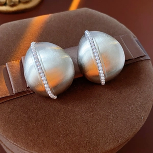 Macro view of silver teardrop earrings with brushed metal texture and small pearls
