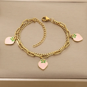 Detail of gold double-layered bracelet with pink strawberry charms on a beige display