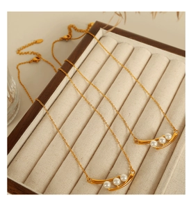 Détail d'une élégante chaîne dorée avec trois perles blanches sur un pendentif incurvé
