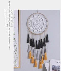 Detailed handmade mandala dream catcher with tri-color tassels on a gray wall