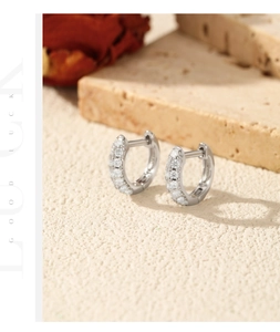 Macro view of geometric S925 sterling silver huggie earrings with sparkling stones