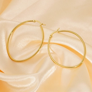 Detail view of large gold oval hoop earrings on elegant silk background fabric