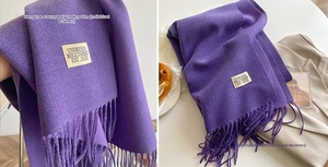Close-up of purple cashmere-like winter scarf with fringe details and woven brand label