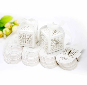 Flat-lay white laser-cut cross favor boxes with ribbons and unpainted flat sheets