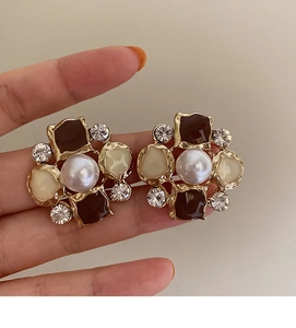 Macro shot of a floral earring with brown oil drip petals and a central white pearl inlay