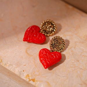 Detail of red heart earrings with textured finish and vintage golden floral studs