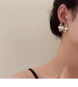 Macro detail of vintage floral pearl stud earring with diamonds worn by a model