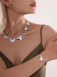 Detalle del conjunto de collar y pulsera de eslabones de corazón plateados sobre modelo