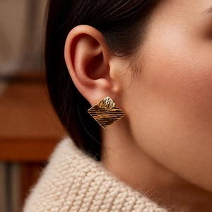 Detail showing 18k gold plated geometric stud earring with ripple texture on a model