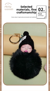 Close-up of sleeping baby plush doll keychain with black faux fur pompom and golden ring