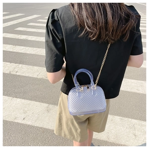 Detail of shell-shaped jelly bag with quilted texture and golden chain strap