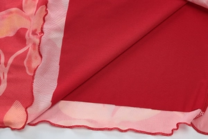 Détail du tissu en mesh à fleurs et de l'ourlet ondulé sur une robe d'été rouge