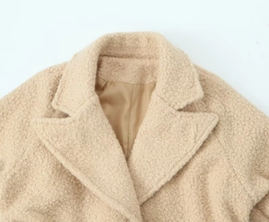 Detailed close-up of heavy beige boucle fabric lapel and warm textured wool coat
