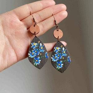 Detail of bohemian wood teardrop earrings featuring hand-painted floral daisy patterns