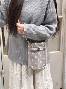 Graue Cord-Umhängetasche mit Polka Dots und Metallverschluss am Modell gezeigt
