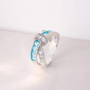 Macro shot of silver criss-cross ring featuring blue square zircons and white pave stones