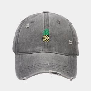 Detail of gray washed canvas baseball cap with yellow pineapple embroidery and distressed holes
