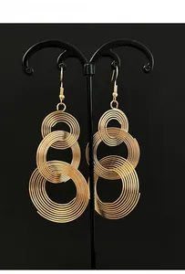 Detailed macro view of triple-layered golden spiral hoop earrings on a black display stand