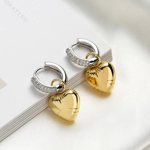 Asymmetric gold heart dangle earrings with zircon-set silver hoops on white silk