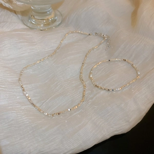 Minimalist silver irregular geometric necklace and bracelet set on white fabric
