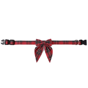 Detail of red plaid fabric dog collar with bow tie, plastic buckle, and silver D-ring