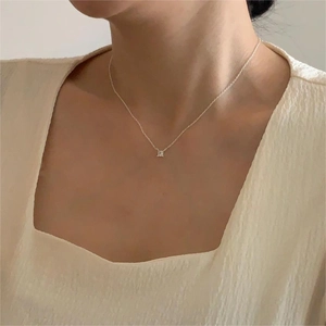 Close-up of minimalist silver chain featuring a square cubic zirconia pendant on a model